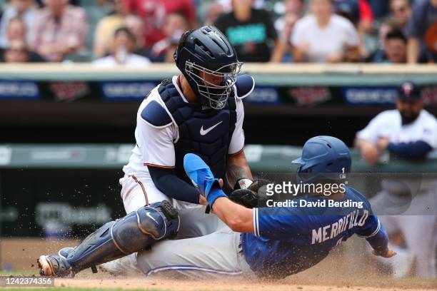 Whit Merrifield of the Toronto Blue Jays scores a run at home plate against Gary Sanchez of the Minnesota Twins in the tenth inning of the game at...