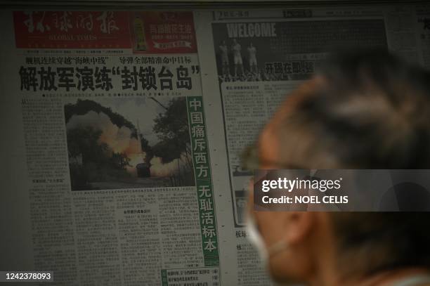 Man reads a newspaper about China's military exercises encircling Taiwan, along a street in Beijing on August 8, 2022.
