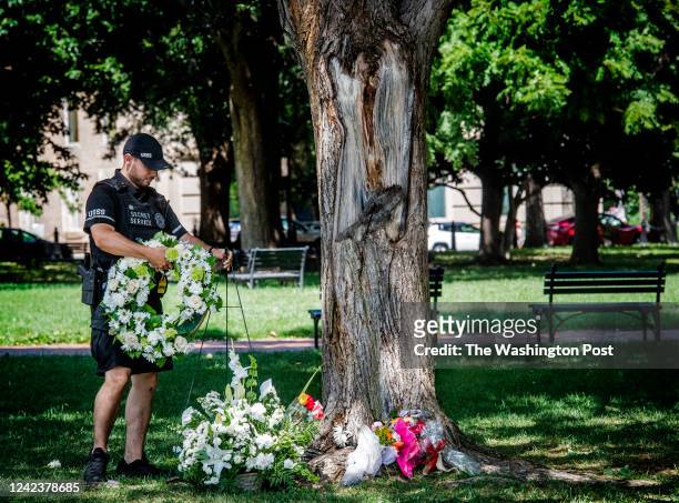 Uniformed Secret Service officer picks up a wreath that has blown off of a makeshift shrine growing at the site of a lightning strike in Lafayette...