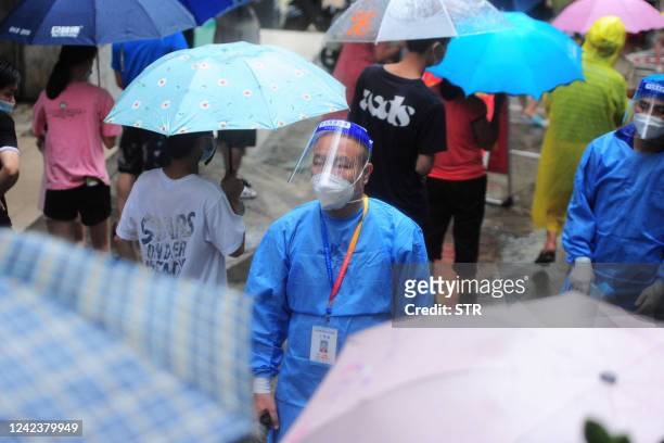 Medical worker looks on as residents and tourists queue to undergo nucleic acid tests for the Covid-19 coronavirus in Sanya in China's southern...