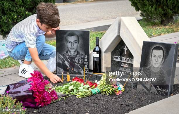 Relative of a Georgian serviceman killed during the 2008 war with Russia over control of South Ossetia place a candle at a grave during a ceremony...