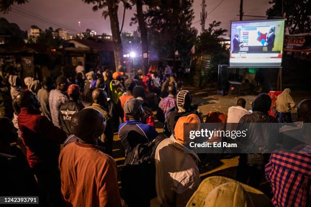 Men watch live news aired on a public projector on the eve of a presidential election in the centre of Kibera informal settlement on August 8, 2022...