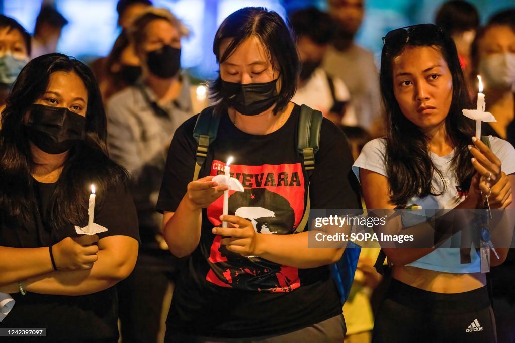 Activists hold a lit candle during the anniversary of the '...
