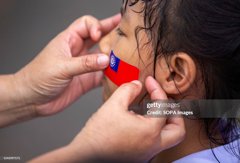 A kid with a Myanmar flag sticker on her face participates...