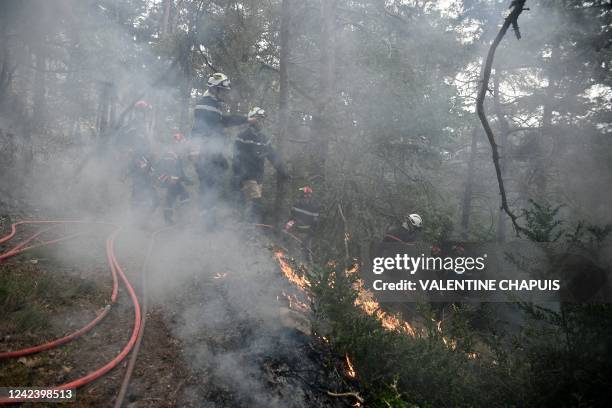 Firefighters light fires in Mostuejouls, southern France, on August 9 as a prophylactic measure aimed at slowing the advance of a fire underway in...