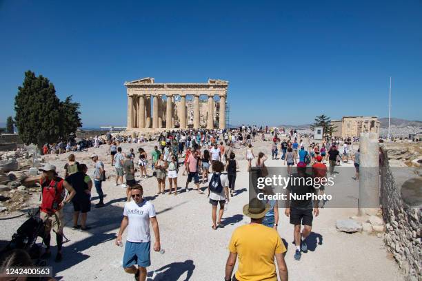 Crowds of tourists and local visitors in front of the Parthenon, an ancient temple dedicated to the goddess Athena, on the Akropolis of Athens on the...