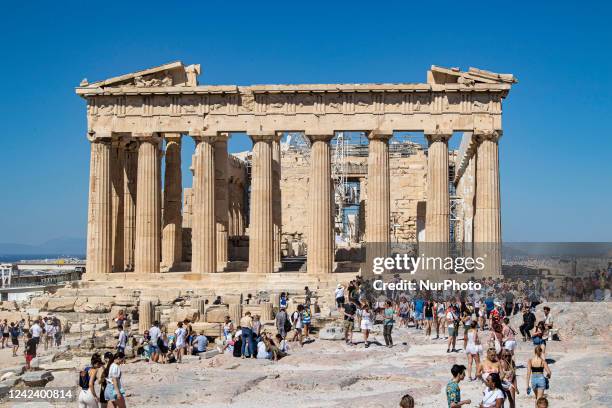 Crowds of tourists and local visitors in front of the Parthenon, an ancient temple dedicated to the goddess Athena, on the Akropolis of Athens on the...