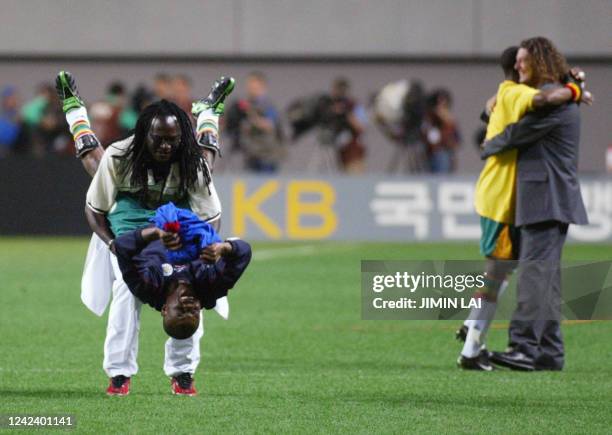 Unidentified members of the Senegalese team celebrate on the pitch with their French coach, Bruno Metsu , following their win over France at the...