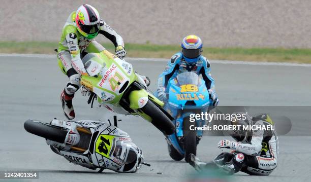 Spain's Ducati rider Aleix Espargaro and France's Honda driver Randy De Puniet crash as Spain's Suzuki driver Alvaro Bautista drives towards them...
