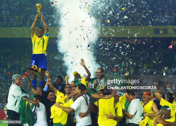 Brazil's team captain and defender Cafu hoists the World Cup trophy over the whole Brazilian team as confetti fall over the pitch during the award...