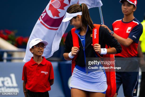 Emma Raducanu of Great Britain talks to the walk-on kid on her way onto the court to play Camila Giorgi of Italy in her first round match on Day 4 of...