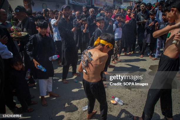 Shiite Muslim devotee beats another's back with chains during mourning procession on Ashura 10th of Muharram, the first month of Islamic Calendar, in...