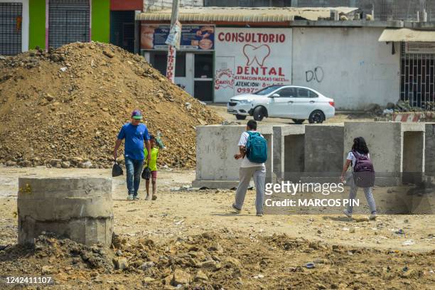 Children returning from school walk down a street in the Ciudad de Dios cooperative in the Monte Sinai sector of Guayaquil, Ecuador, on July 26,...
