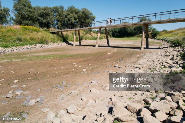 People walk on a bridge over a dried out river on the banks of the Waal river on August 10, 2022 in Nijmegen, Netherlands. The ongoing drought and...