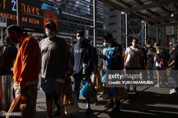 Group of migrants wait in line after arriving from Texas, outside Port Authority Bus Terminal to receive humanitarian assistance on August 10, 2022...