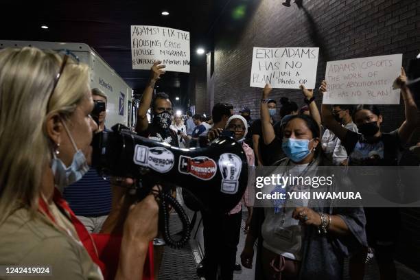 Protesters hold sign while a group of migrants arrive at Port Authority Bus Terminal from Texas on August 10, 2022 in New York. - Texas has sent...