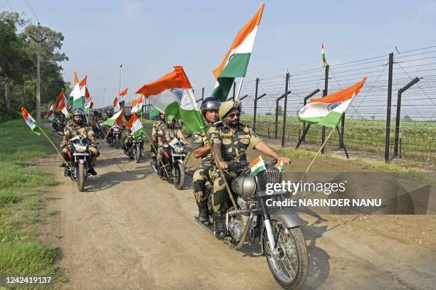 Indian Border Security Force soldiers take part in a motorbike rally along the fence carrying India's national flags as part of the celebrations...