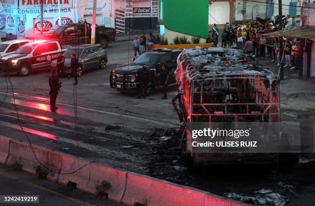 Members of the State Prosecutor's Office and Municipal Police guard the area where gang members set a bus on fire blocking a highway to prevent...