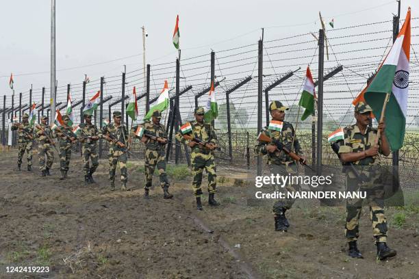 Indian Border Security Force soldiers patrol along the fence carrying India's national flags as part of the celebrations ahead of the 75th...