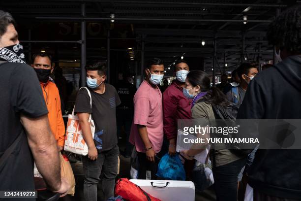 Group of migrants wait in line outside Port Authority Bus Terminal to receive humanitarian assistance on August 10, 2022 in New York. - Texas has...