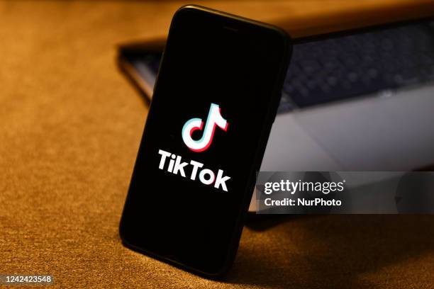 TikTok logo displayed on a phone screen and a laptop are seen in this illustration photo taken in Krakow, Poland on August 10, 2022.