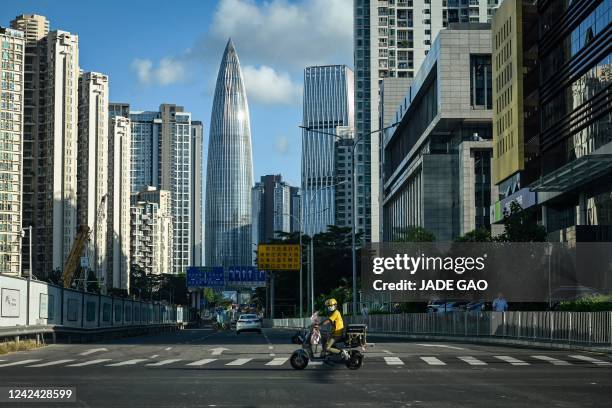 This photo taken on July 20 shows a delivery worker riding a scooter on a street in Shenzhen, in China's southern Guangdong province.