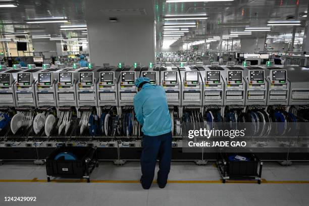 This photo taken on July 20, 2022 shows a worker operating a machine on a smartphone production line at the Oppo factory in Dongguan, China's...