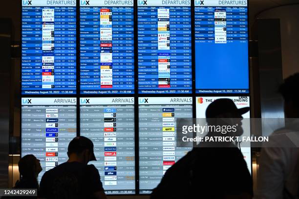 Passengers look at flight departure information boards in the West Gates expansion area at Los Angeles International Airport in Los Angeles,...