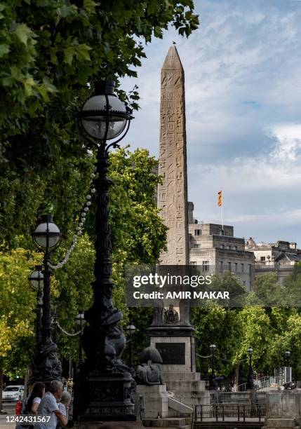 People stand along the Thames river embankment near the ancient Egyptian Obelisk of Thutmose III , known as "Cleopatra's Needle", in London on July...