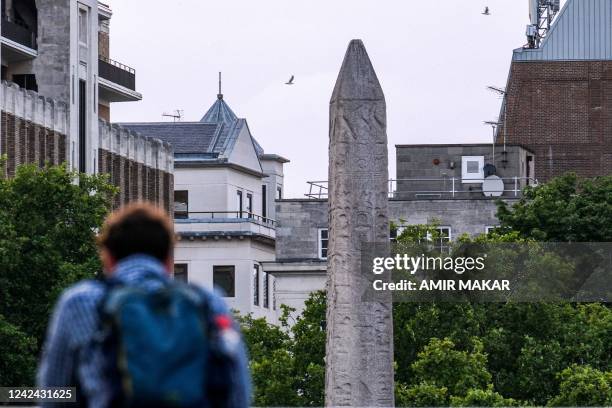Person stands along the south bank of the Thames river across from the ancient Egyptian Obelisk of Thutmose III , known as "Cleopatra's Needle", in...