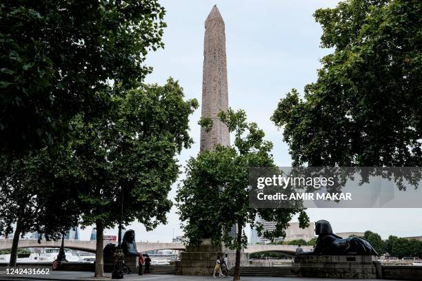 People walk past the ancient Egyptian Obelisk of Thutmose III , known as "Cleopatra's Needle", along the Thames river embankment in London on August...