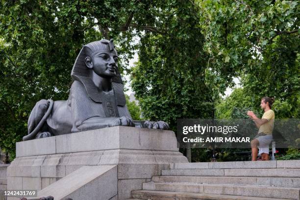 Tourist photographs one of the two bronze sphinxes, sculpted in 1878 in the image and bearing the cartouche of the ancient Egyptian Pharaoh Thutmose...