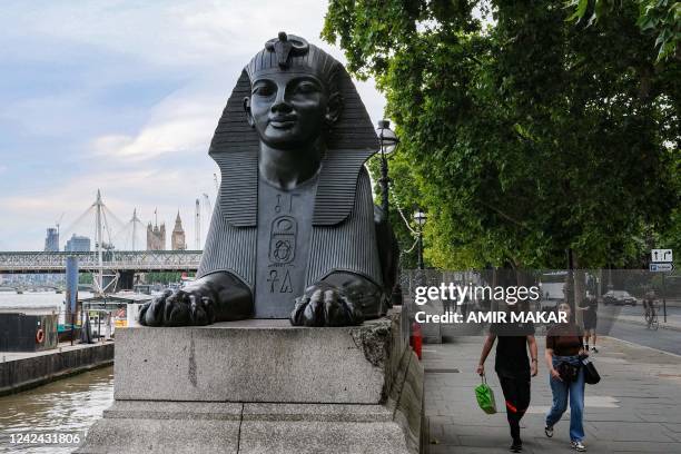 People walk past one of the two bronze sphinxes, sculpted in 1878 in the image and bearing the cartouche of the ancient Egyptian Pharaoh Thutmose III...