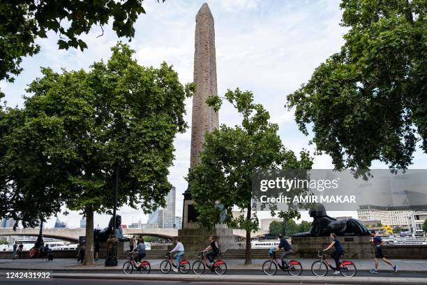 Cyclists ride past the ancient Egyptian Obelisk of Thutmose III , known as "Cleopatra's Needle", along the Thames river embankment in London on July...