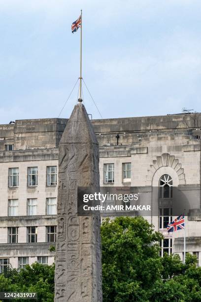The British unionjack flag flies atop a building behind the ancient Egyptian Obelisk of Thutmose III , known as Cleopatra's Needle", along the Thames...