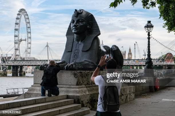 Tourists photograph one of the two bronze sphinxes, sculpted in 1878 in the image and bearing the cartouche of the ancient Egyptian Pharaoh Thutmose...