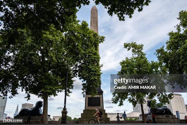 Cyclist rides past the ancient Egyptian Obelisk of Thutmose III , known as "Cleopatra's Needle", along the Thames river embankment in London on July...