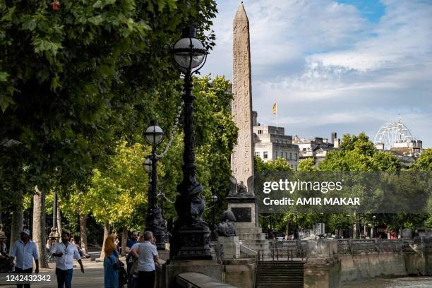 People walk along the Thames river embankment near the ancient Egyptian Obelisk of Thutmose III , known as "Cleopatra's Needle", in London on July...