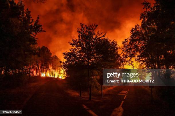 Picture taken overnight on August 11, 2022 shows a silhouette on a road near burning trees at a wildfire near Belin-Beliet, southwestern France. -...