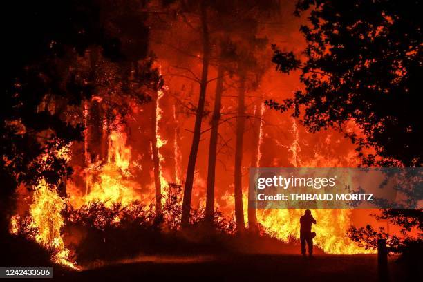 Silhouette is seen in front of flames at a wildfire near Belin-Beliet, southwestern France, overnight on August 11, 2022. - French officials warned...