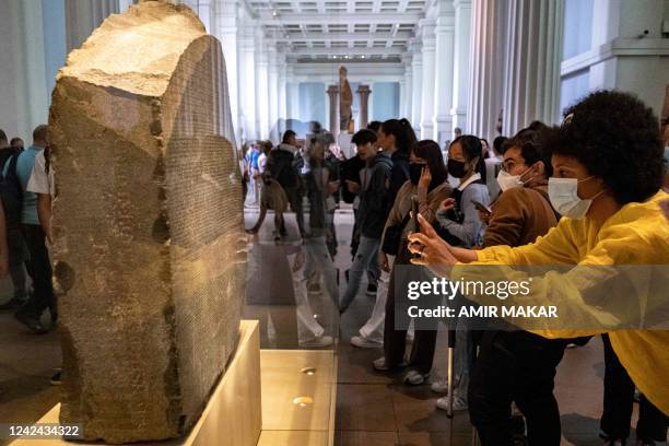 Visitors view the Rosetta Stone at the British Museum in London on July 26, 2022. - The Rosetta Stone a basalt slab dating from 196 BC which bore...