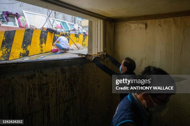 Workers clear debris from a waterlogged, mud-covered basement flat known as "banjiha" in the Gwanak district of Seoul on August 11 after flooding...