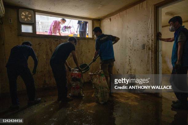 Workers clear a waterlogged, mud-covered basement flat known as "banjiha" in the Gwanak district of Seoul on August 11 after flooding caused by...
