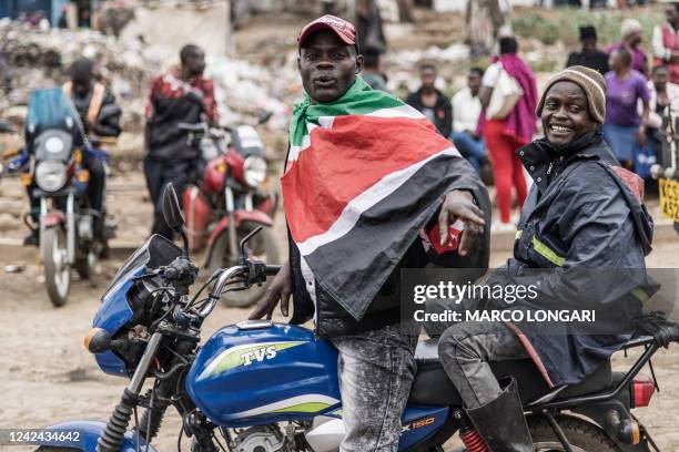 Boda-boda driver wears a Kenyan national flag as he drives a customer through the alleys of Kibera in Nairobi, on August 11, 2022.