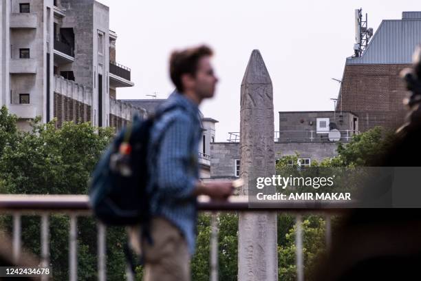 Person stands along the south bank of the Thames river across from the ancient Egyptian Obelisk of Thutmose III , known as "Cleopatra's Needle", in...