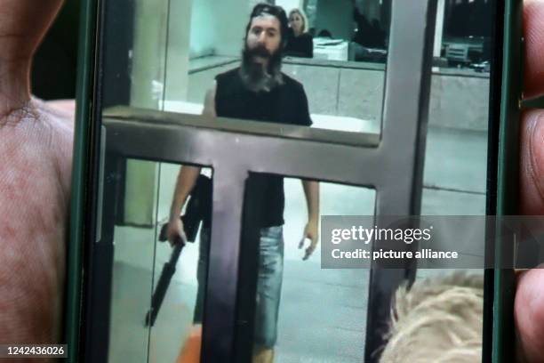 August 2022, Lebanon, Beirut: A man holding a smartphone shows a screen grab taken from a video of an armed depositor gesturing at employees of a...