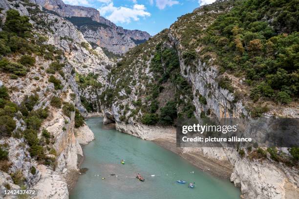 August 2022, France, Aiguines: Canoes enter the Verdon Gorge at the Lac de Sainte-Croix reservoir during low water despite the closure. Heat and lack...