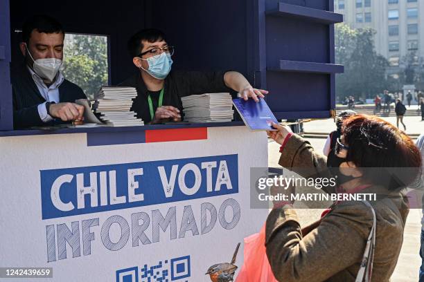 Woman receives a copy of the draft of Chile's new constitution in front La Moneda presidential palace in Santiago, on August 11, 2022. - Chile votes...