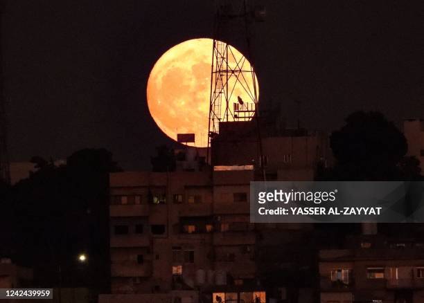 The Sturgeon full moon rises above buildings in the Jornanian capital Amman, on August 11, 2022.