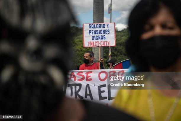 Demonstrator holds a banner that reads "Salary And Decent Pensions" during a workers's rights protest in Caracas, Venezuela, on Thursday, Aug. 11,...